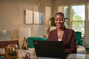 Woman sitting at desk looking at her laptop.